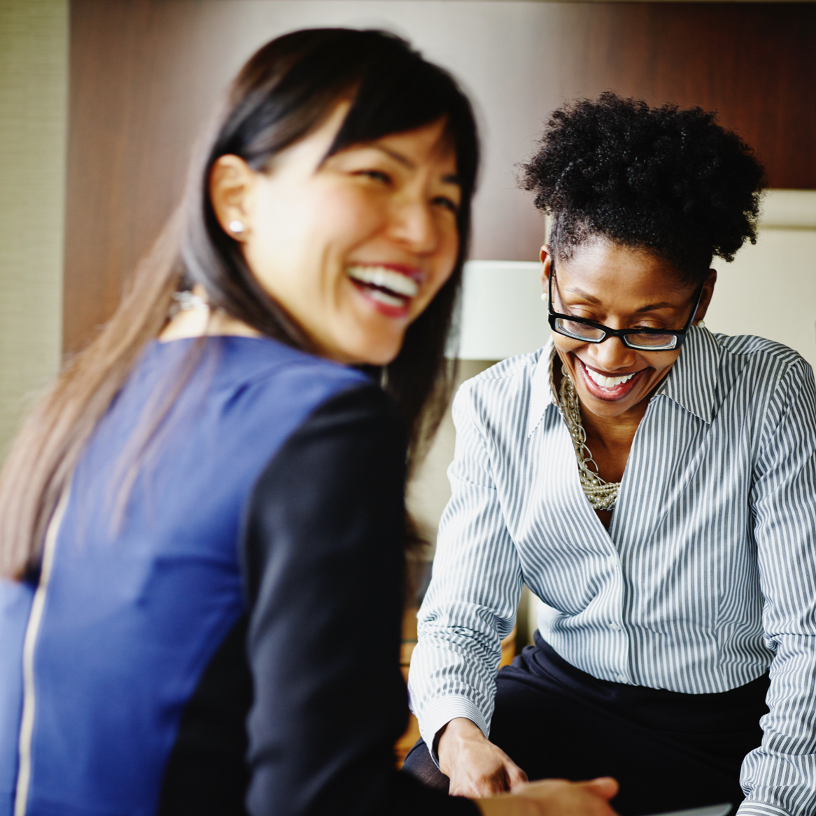 A group of career women smiling and working in a hotel suite.