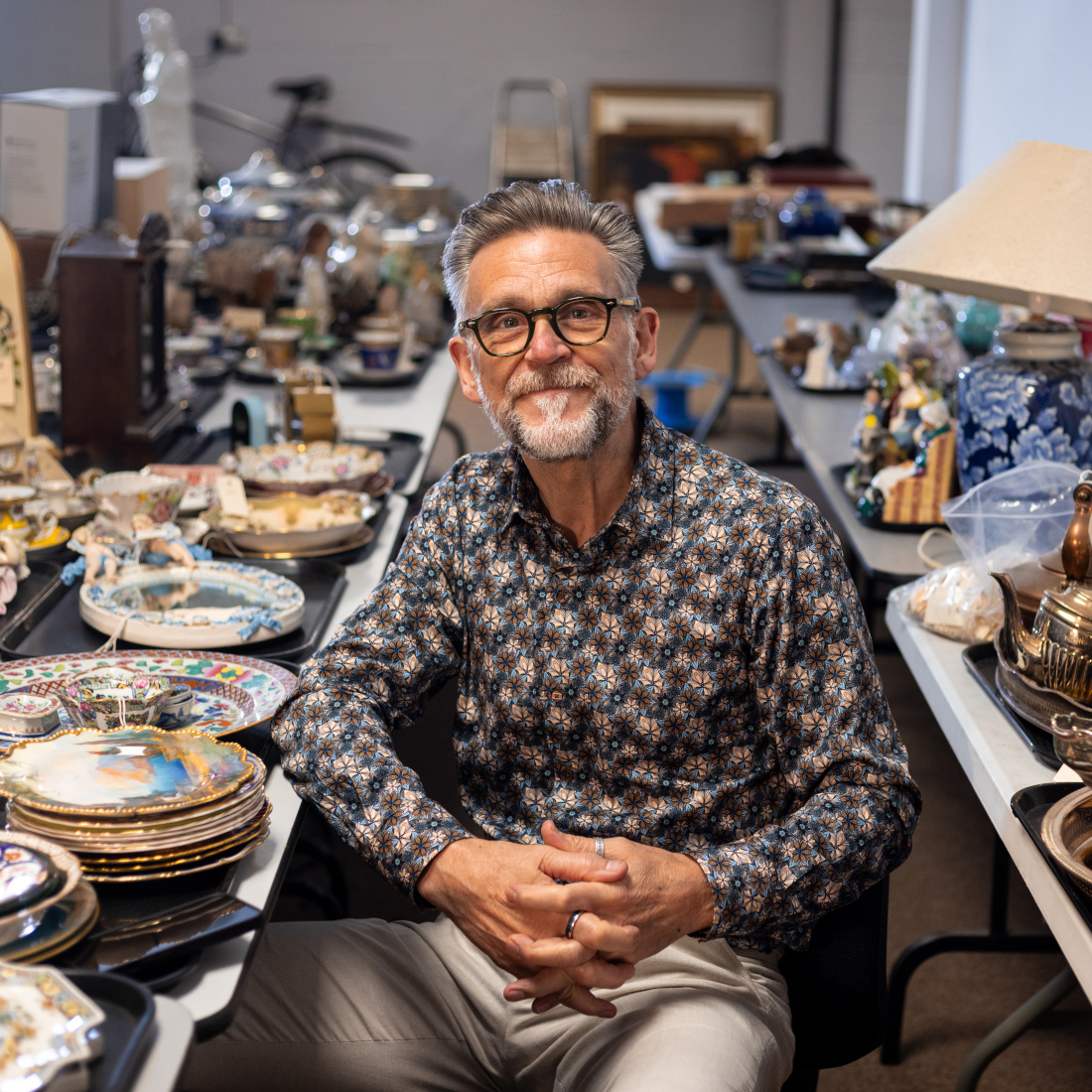 Man sits by collection of antiques
