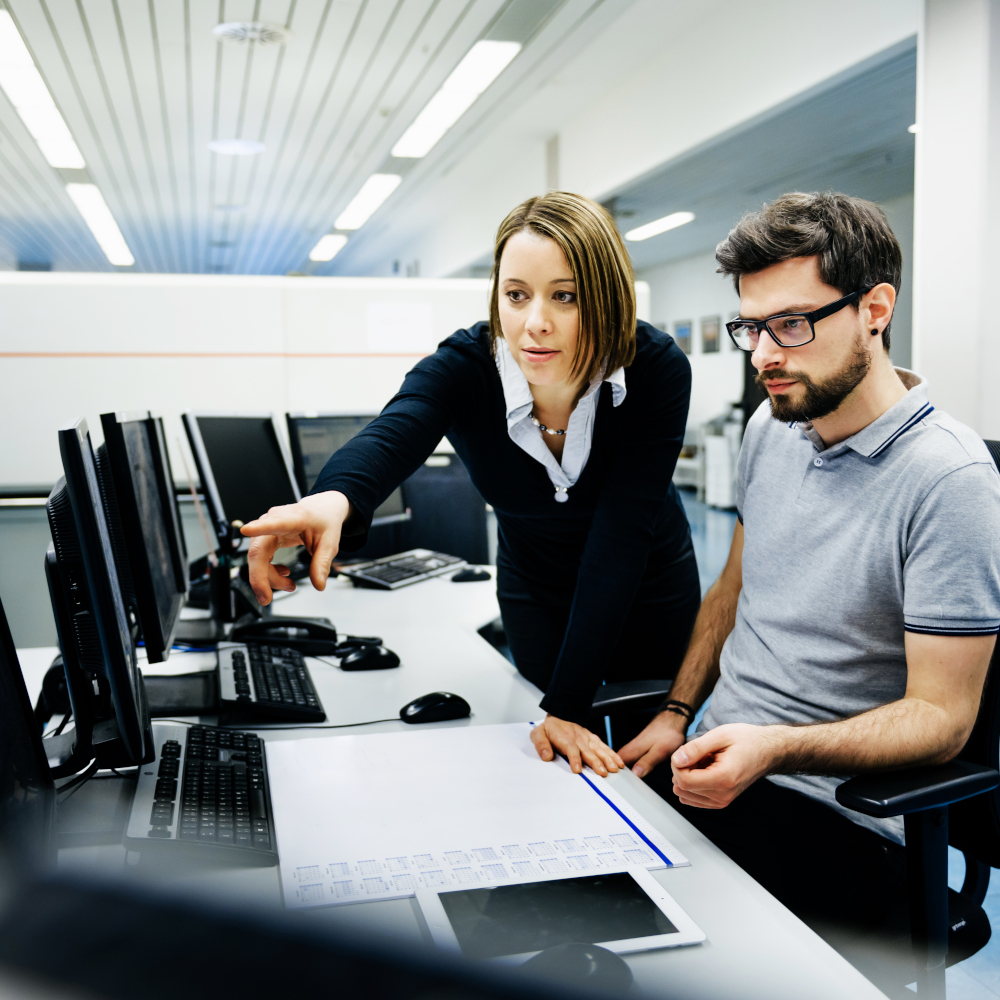 Woman points at monitor man is working at