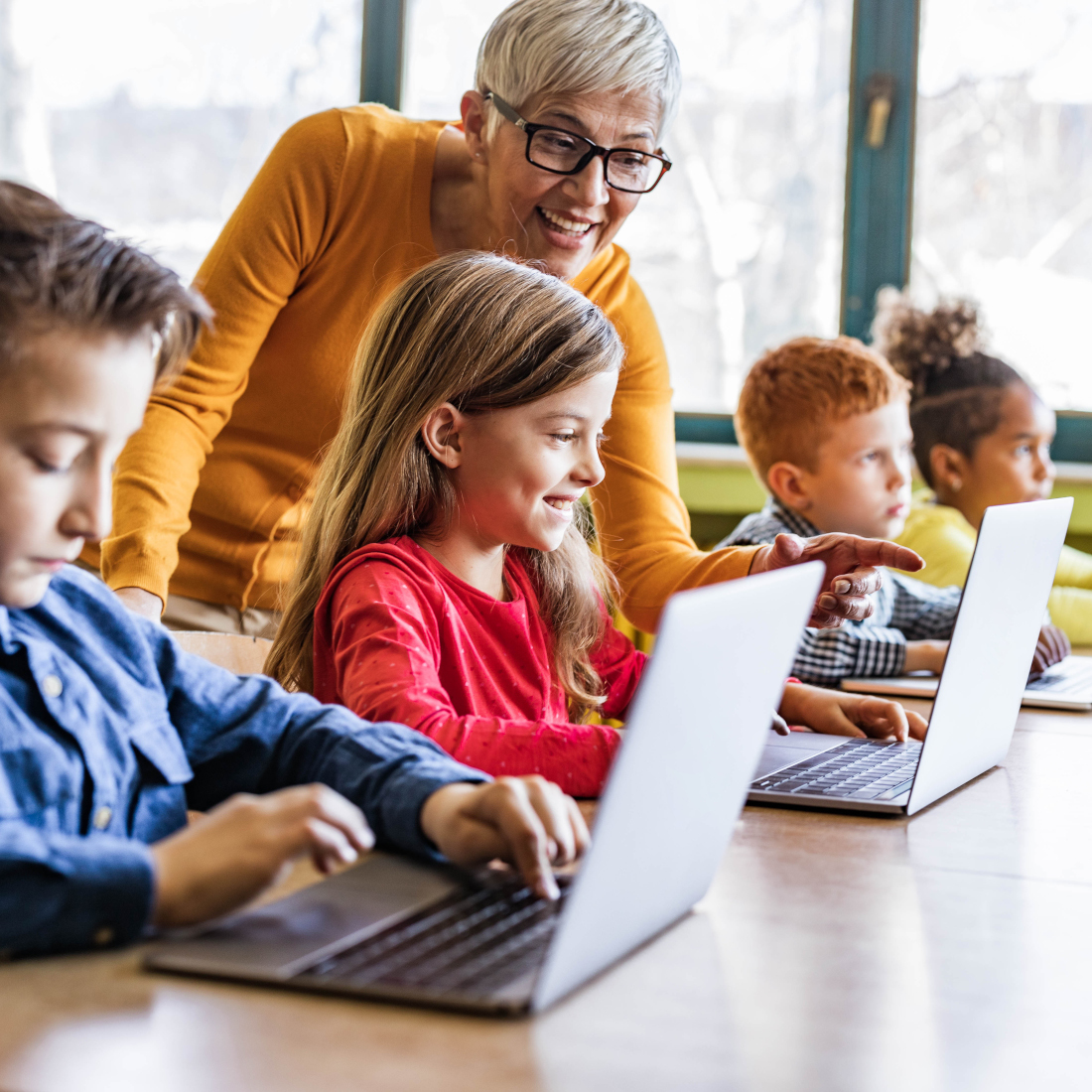 Teacher smiles and points at students laptop