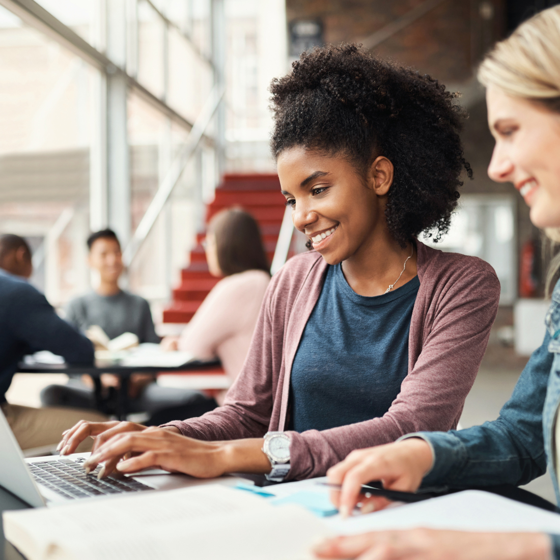 Two women smile while looking at laptop