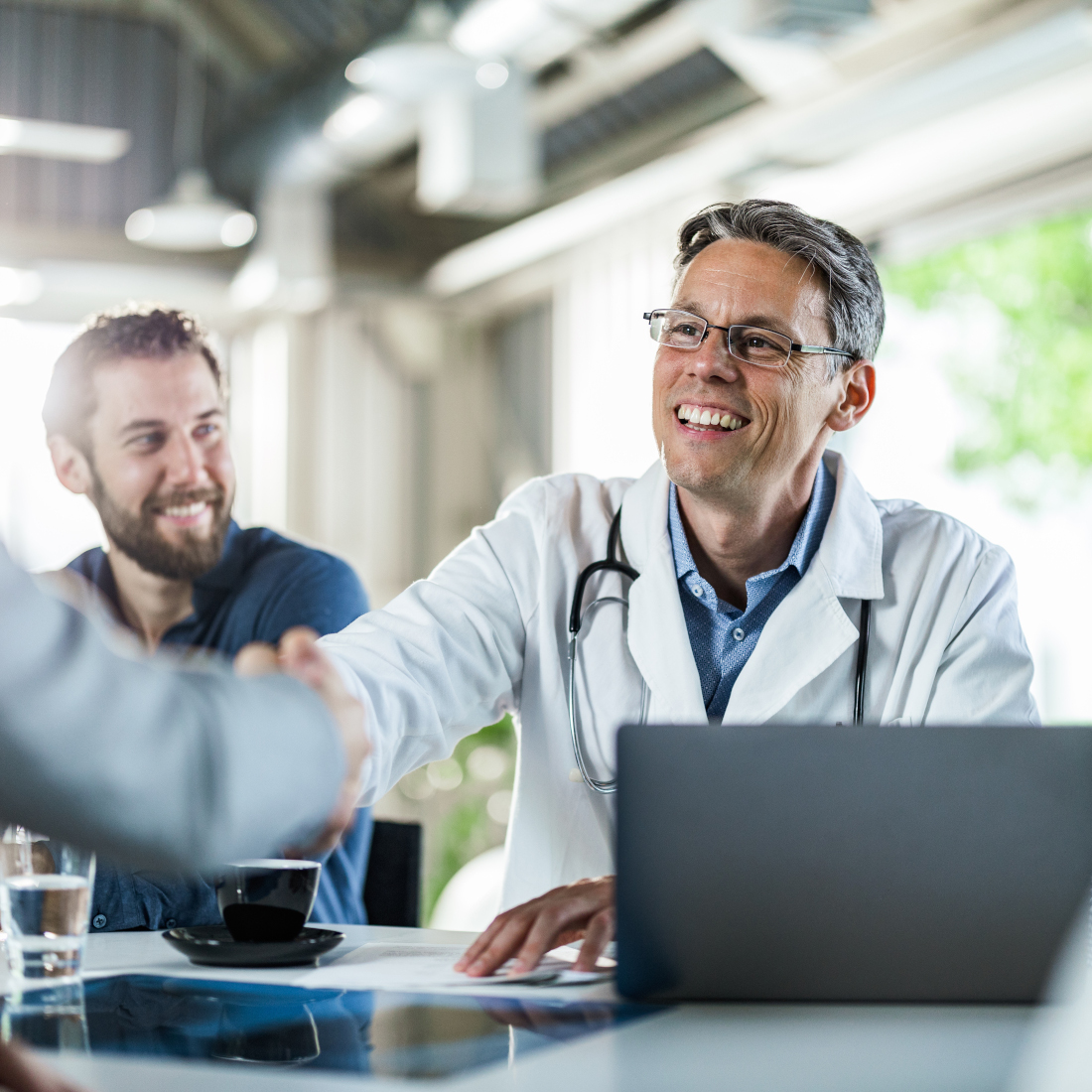 Doctor shakes hands with person across a table