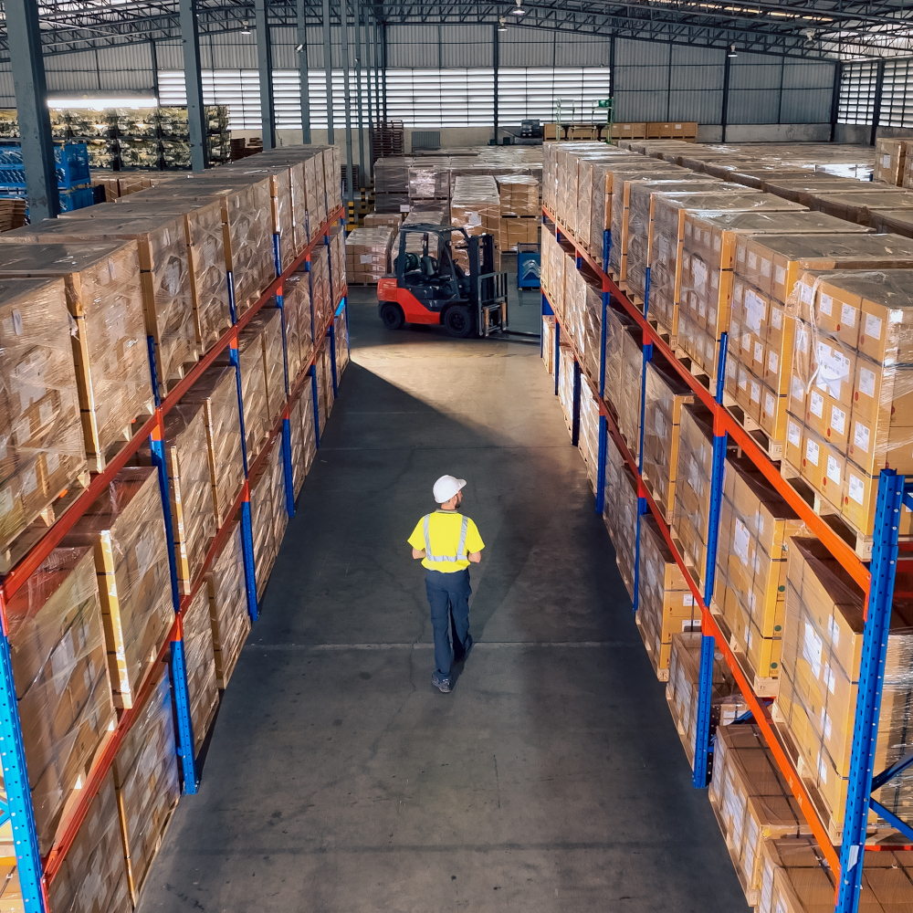 Worker walks down warehouse aisle